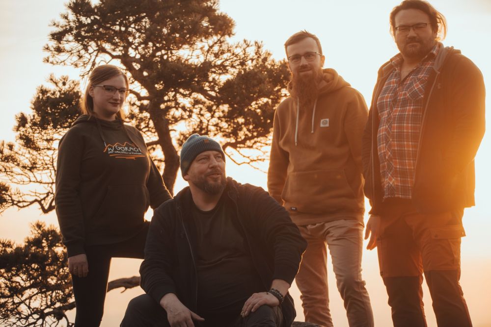 Cztery osoby z zespołu, trzech mężczyzn i jedna dziewczyna, wszyscy opierają się o mostek.