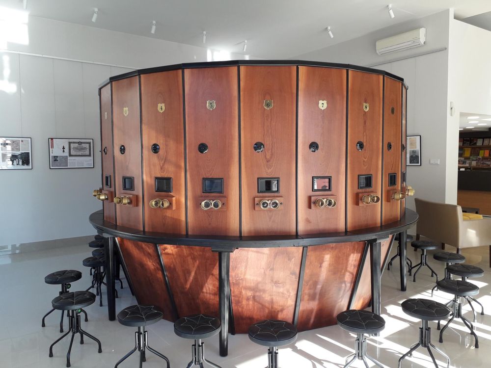 Drewniane urządzenie na planie koła. Posiada wizjery, przez które można oglądać pokaz fotografii. Dookoła niego stoją krzesełka dla oglądających.