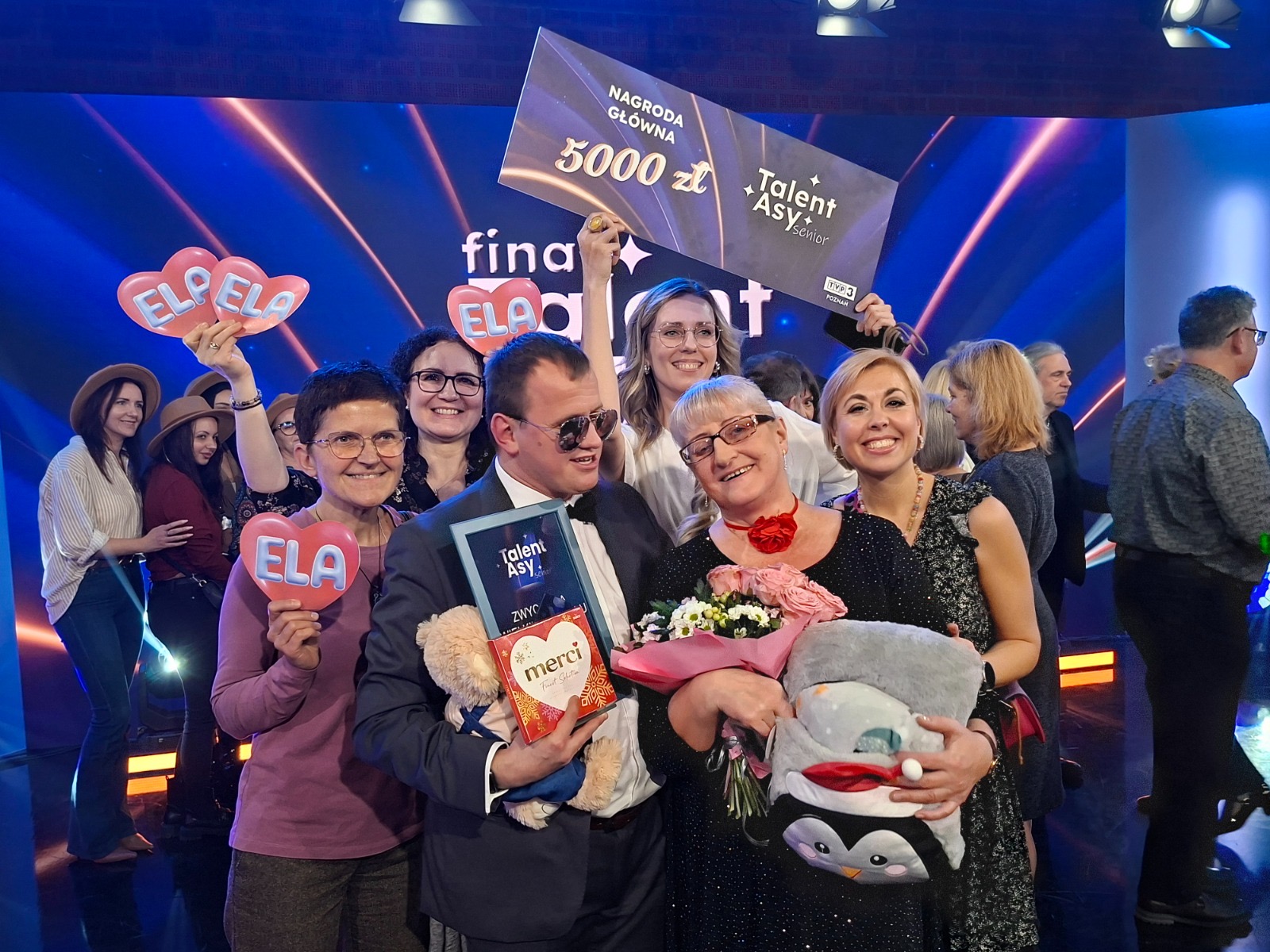 Elżbieta Maciejewska i Łukasz Pawlik z nagrodami i prezentami od bliskich, obok pracownicy "Klubu Winogrady" z serduszkami z napisem "ELA".