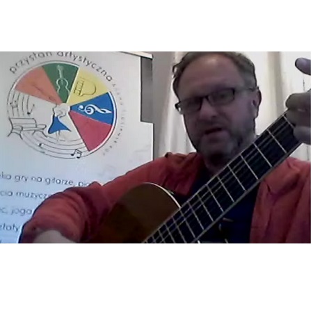 Męszczyzna gra na gitarze. Po lewej logo Przystani Artystycznej.