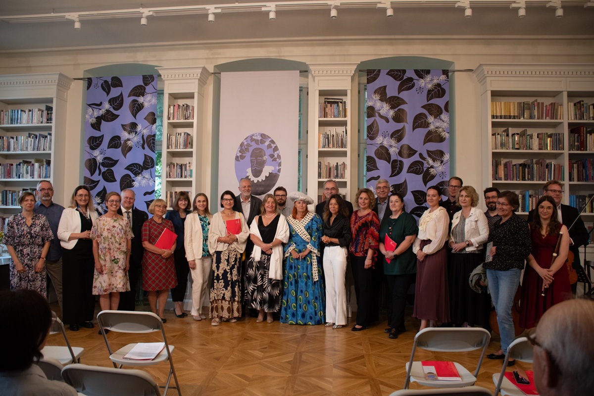 grupa kilkunastu osób kobiet i mężczyzn pozuje do wspólnego zdjęcia w eleganckiej zabytkowej sali