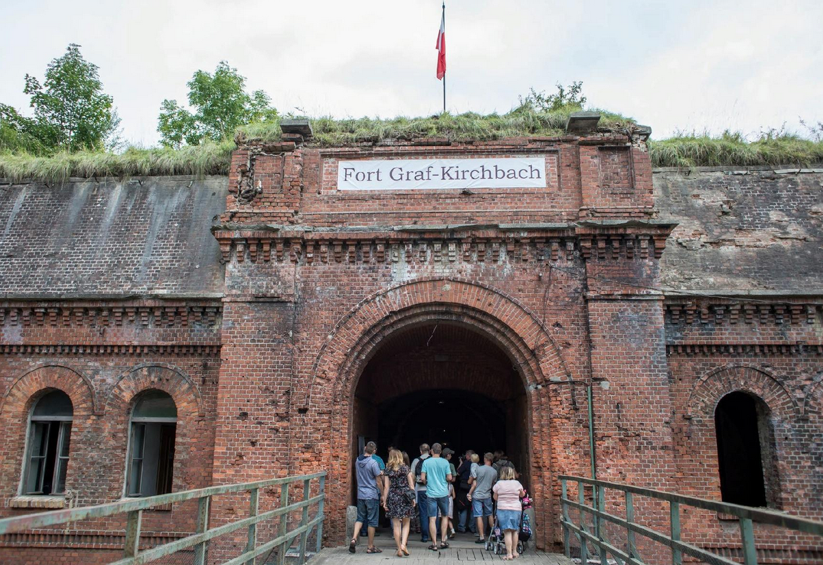 grupa ludzi przy wejściu do zabytkowej budowli fortyfikacyjnej