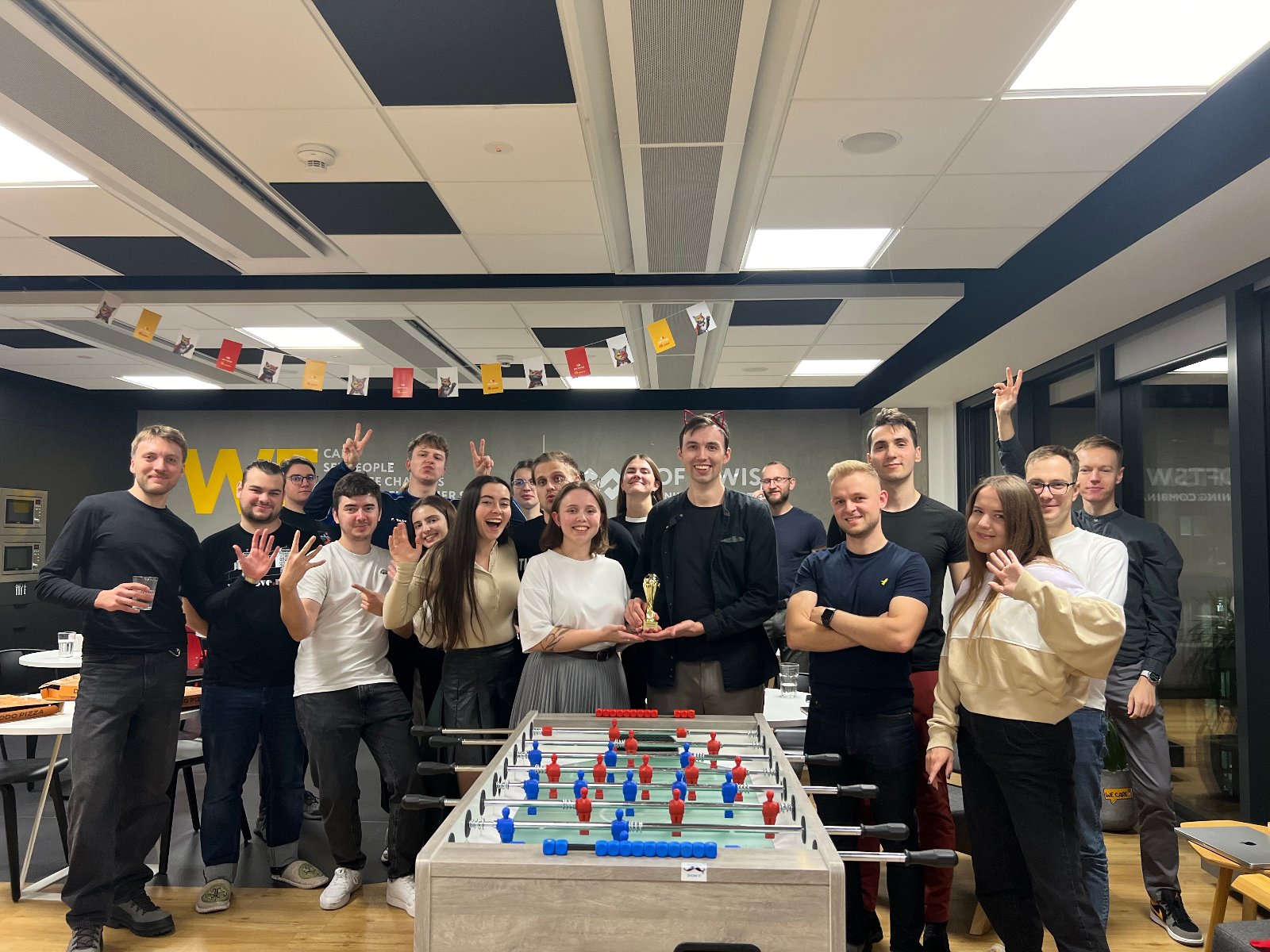 Grupa uśmiechniętych ludzi pozuje ze złotą statuetką.