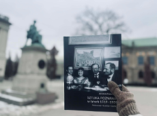 Ktoś trzyma książkę na tle zabytkowego budynku Muzeum Narodowego