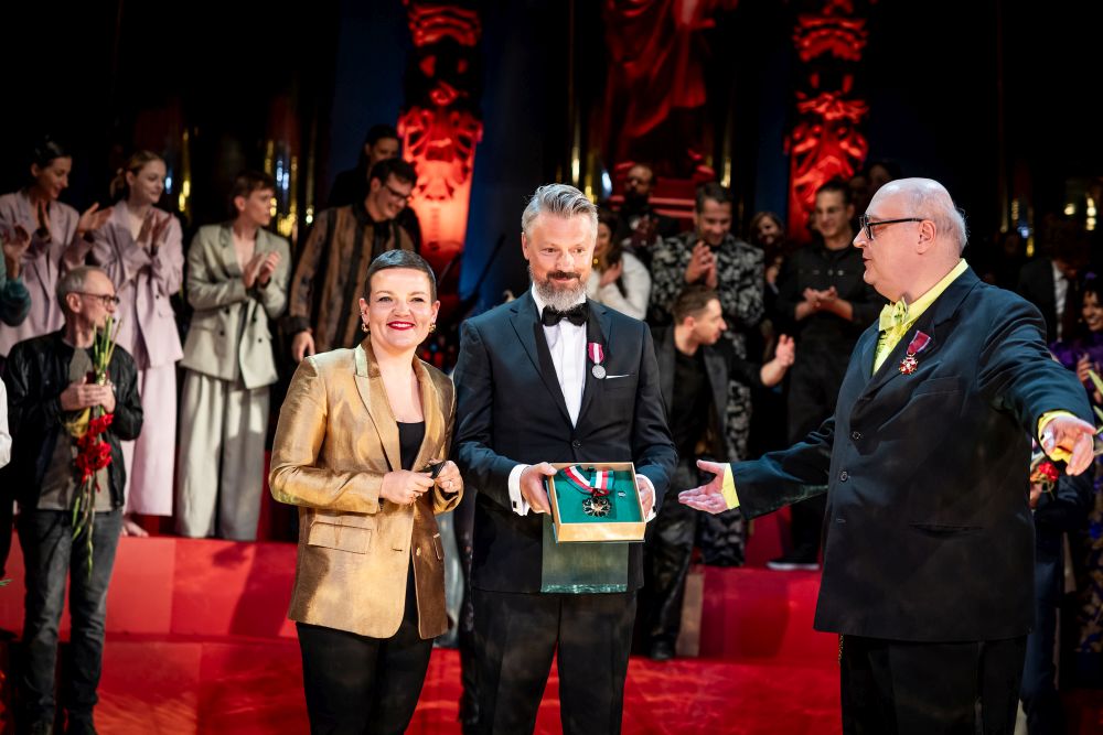 Laureaci pozują z medalem do zdjęcia stojąc na scenie.