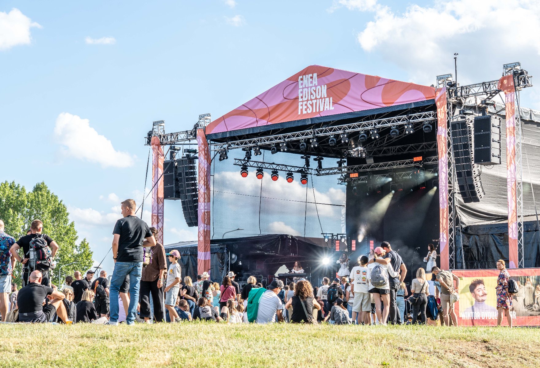 Letni festiwal, widoczna scena, ludzie bawiący się na trawie