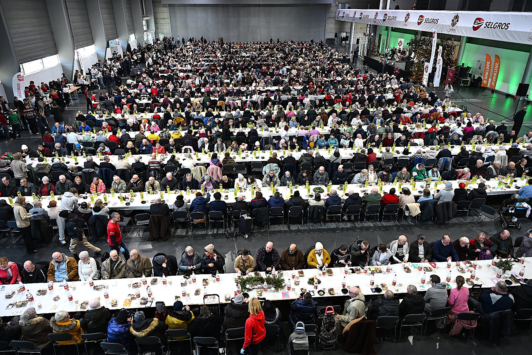 Ludzie siedzący przy zastawionych stołach na Wigilii Caritas