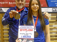 Marta Bereszyńska ze złotem MP młodziczek w zapasach, fot. Maciej Kula - zawodniczka w niebieskim klubowym stroju stoi z dyplomem i medalem na szyi, a za nią stoi trener w klubowym dresie z medalem