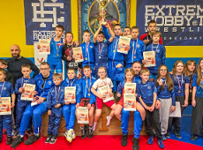 Memoriał Bogdana Brody w zapasach, fot. Maciej Kula - kilkanaścioro zawodników w strojach klubowych Sobieskiego siedzi i stoi z trenerami. Większość z nich ma medale oraz część z nich ma dyplomy