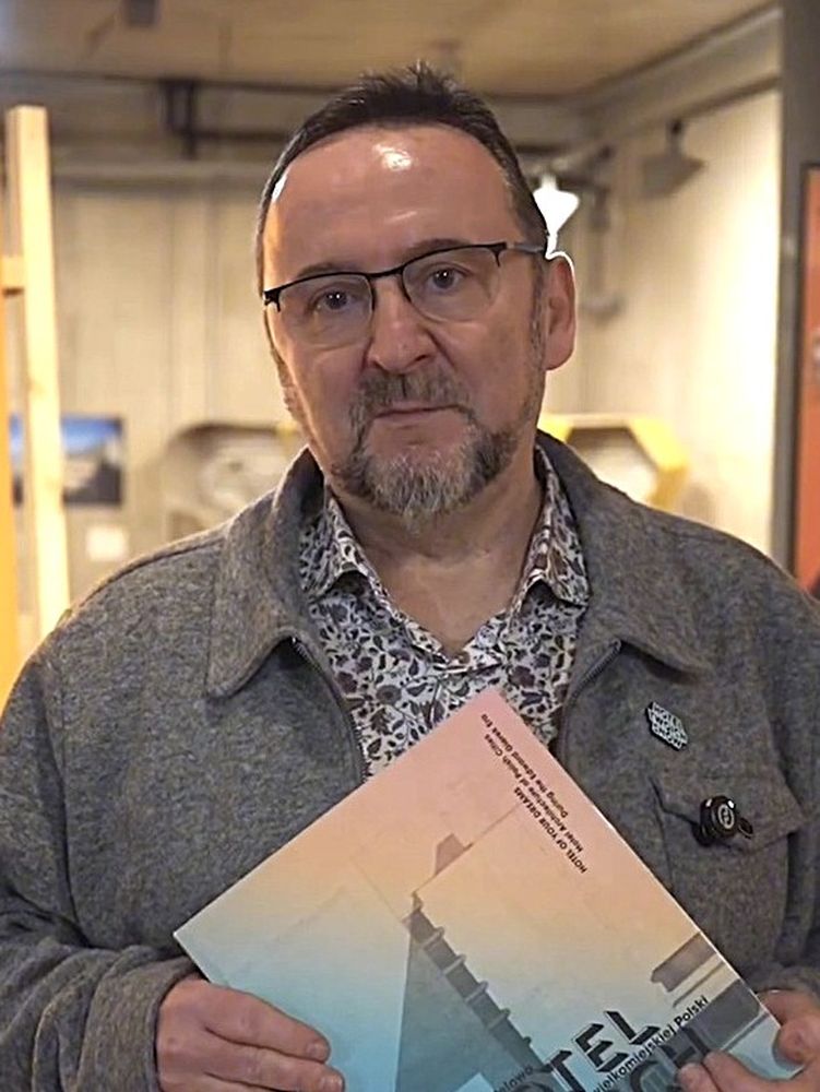 Mężczyna w okularach trzyma w rękach książkę.