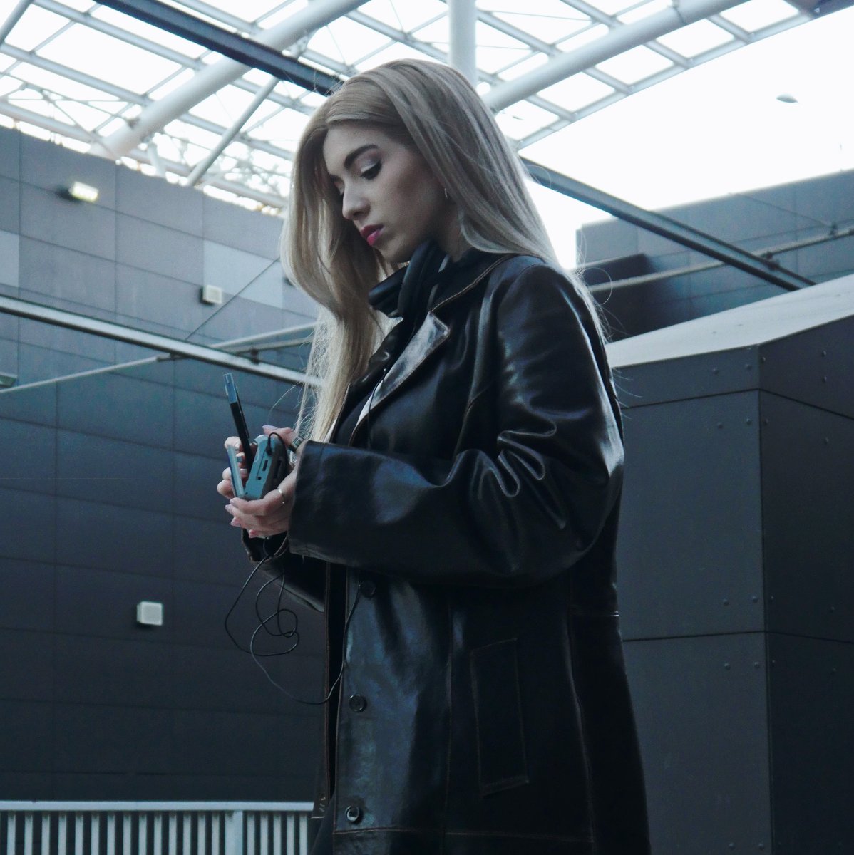 Młoda kobieta w skózarzen kurtce wkłada kasetę do walkmana.