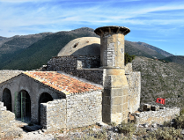 Na zdjęciu budowla wśród gór, na niej widać flagę Albanii