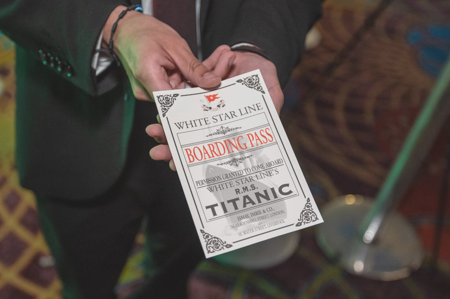 Na zdjeciu dłonie mężczyzny podającego kartę pokładową, będącą biletem na wystawę pod tytułem "Titanic: The Artifact Exhibition".