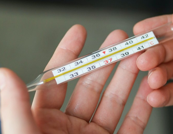 Na zdjęciu dłonie trzymające termometr rtęciowy