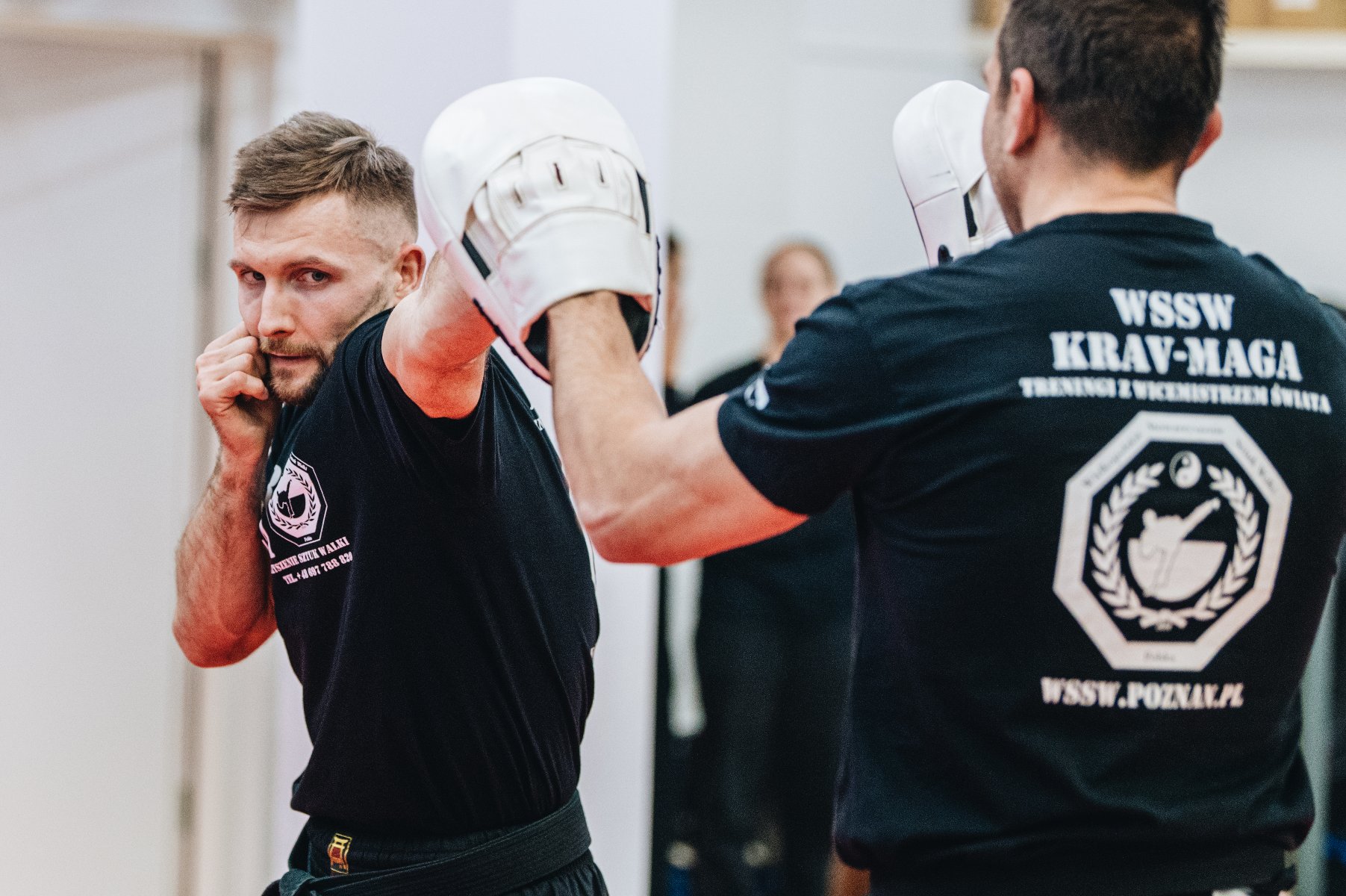 Na zdjęciu dwaj mężczyźni podczas szkolenia sztuk walki, jeden zadaje cios, drugi się broni
