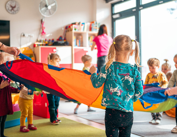 Na zdjęciu dzieci bawiące się kolorową chustą