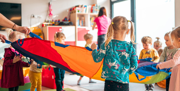 Na zdjęciu dzieci bawiące się kolorową chustą