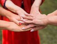 Na zdjęciu kobiece dłonie złożone razem we wspólnym geście, jedna na drugiej