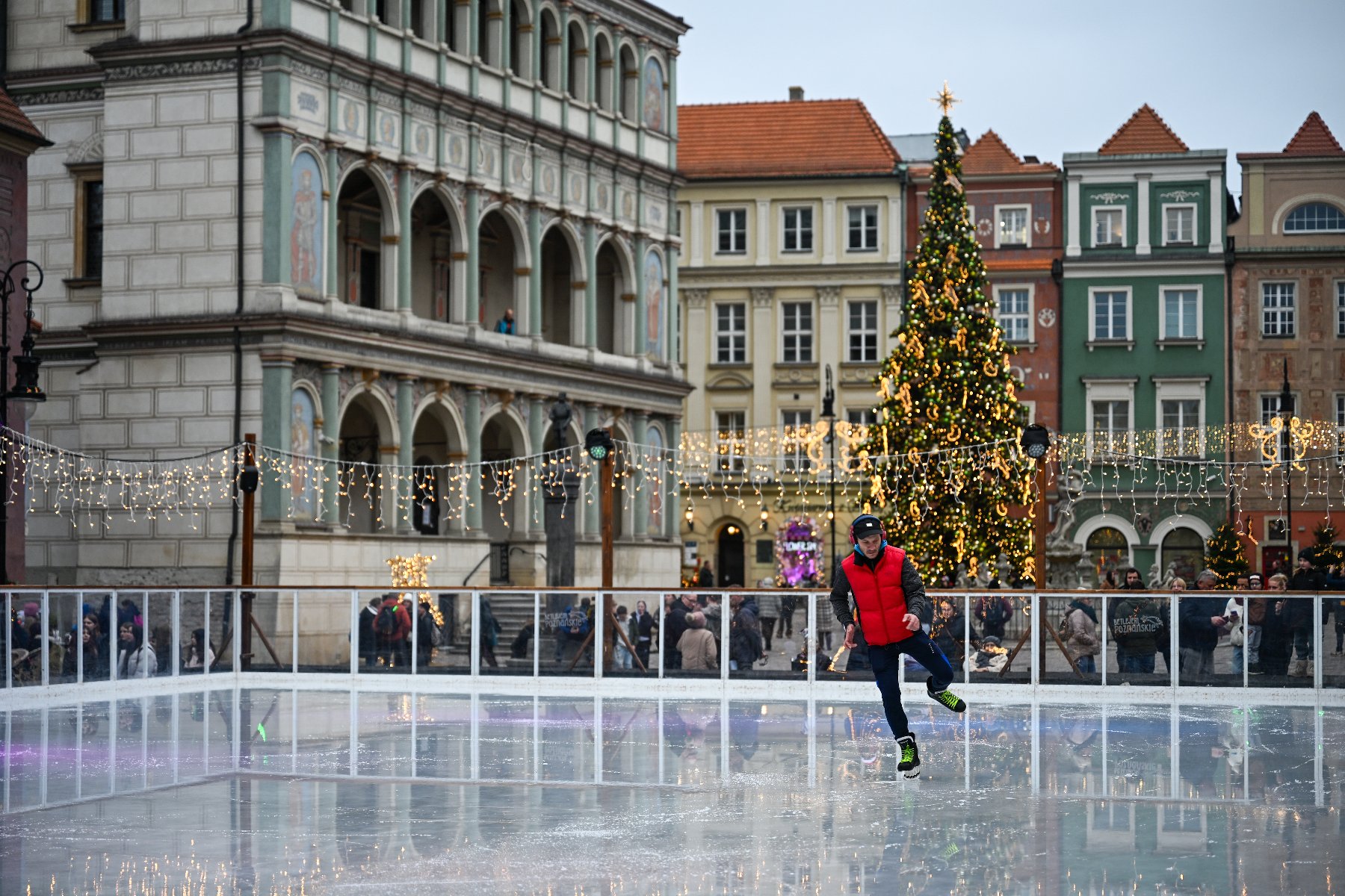 Na zdjęciu lodowisko na Starym Rynku, na nim łyżwiarz, w tle Ratusz