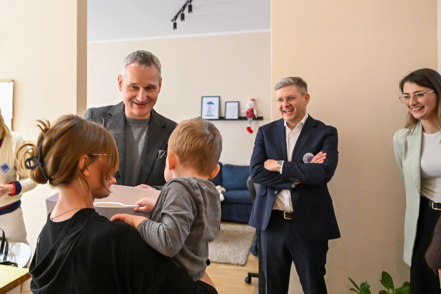 Na zdjęciu małe dziecko maszerujące w stronę łóżka, na którym leżą misie