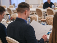 Na zdjęciu mężczyzna czytający dokument w otwartej teczce, siedzący tyłem