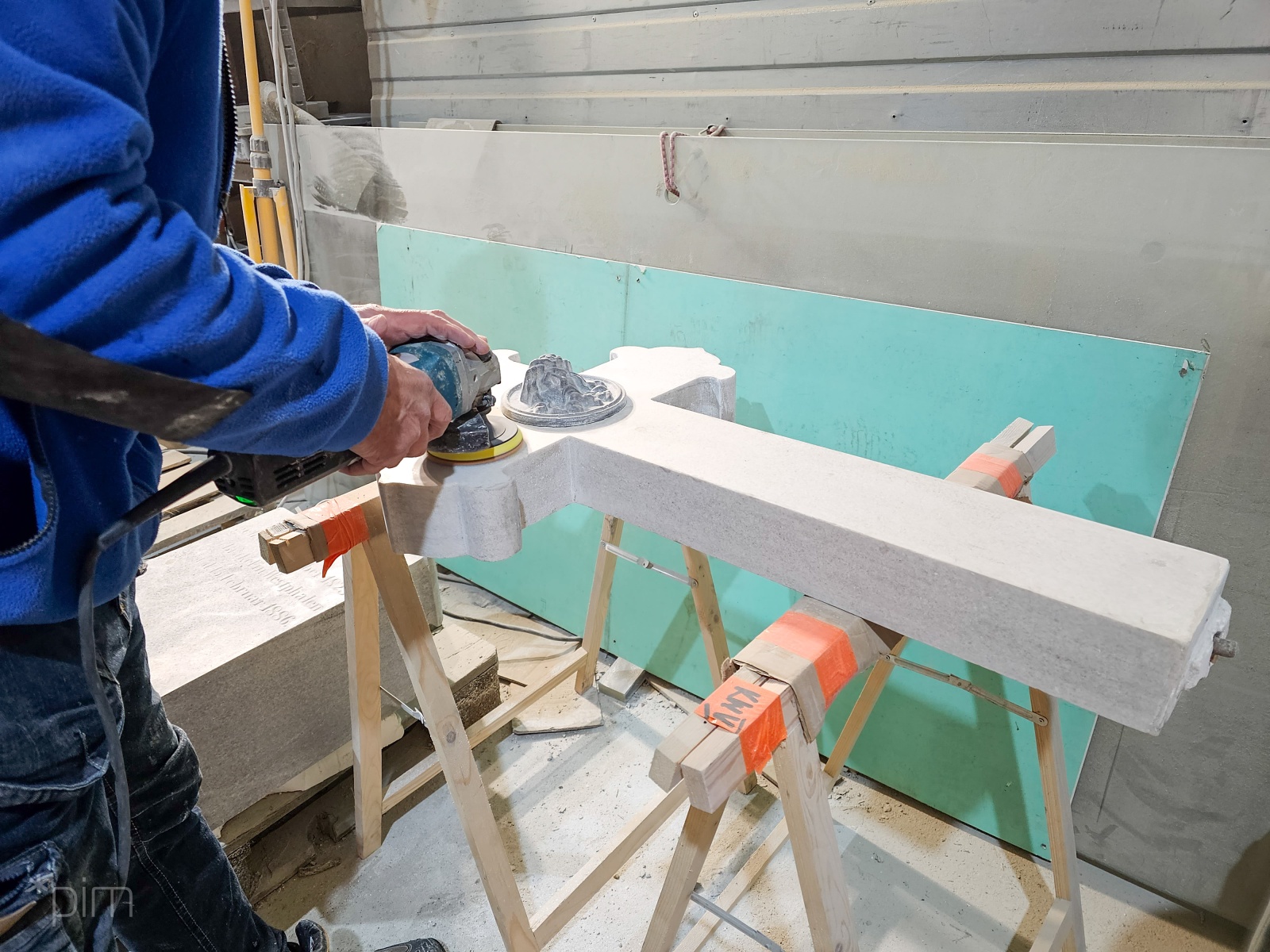 Na zdjęciu mężczyzna polerujący zabytkowy krzyż