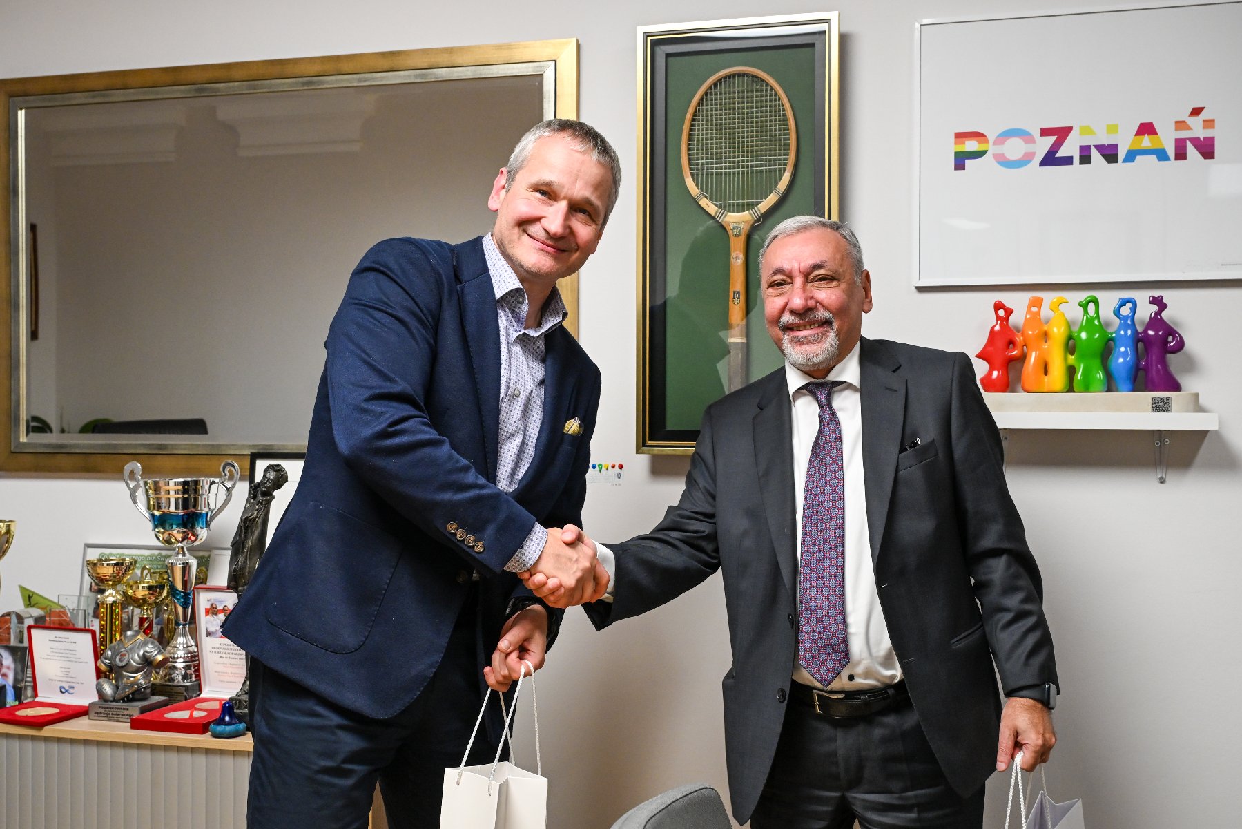 Na zdjeciu mężczyzna wpisujący coś do ogromnej księgi, przed nim stoją dwie flagi, Polski i Armenii