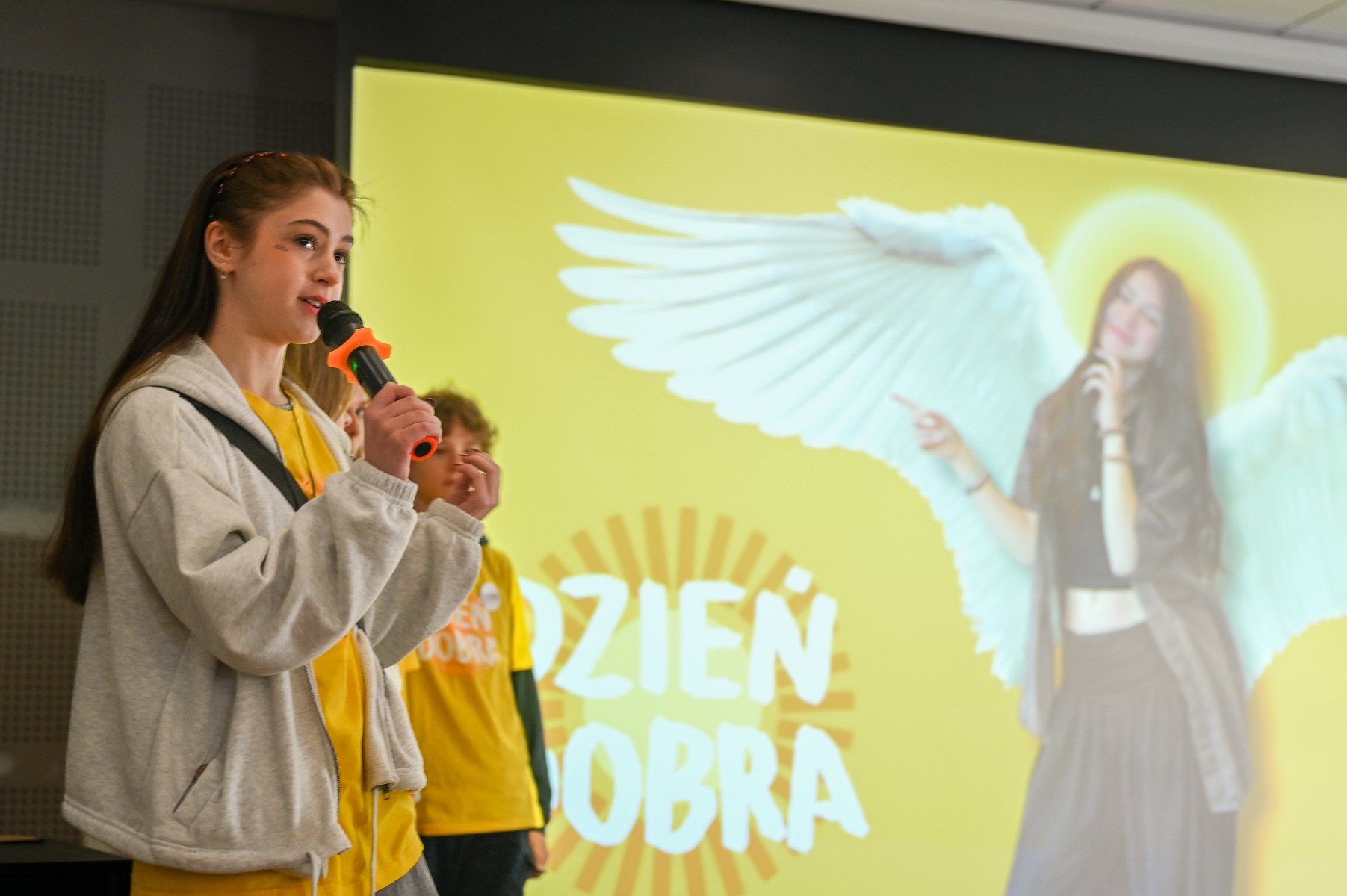 Na zdjęciu młode dziewczyny siedzące na krzesłach, czytające folder o wolontariacie