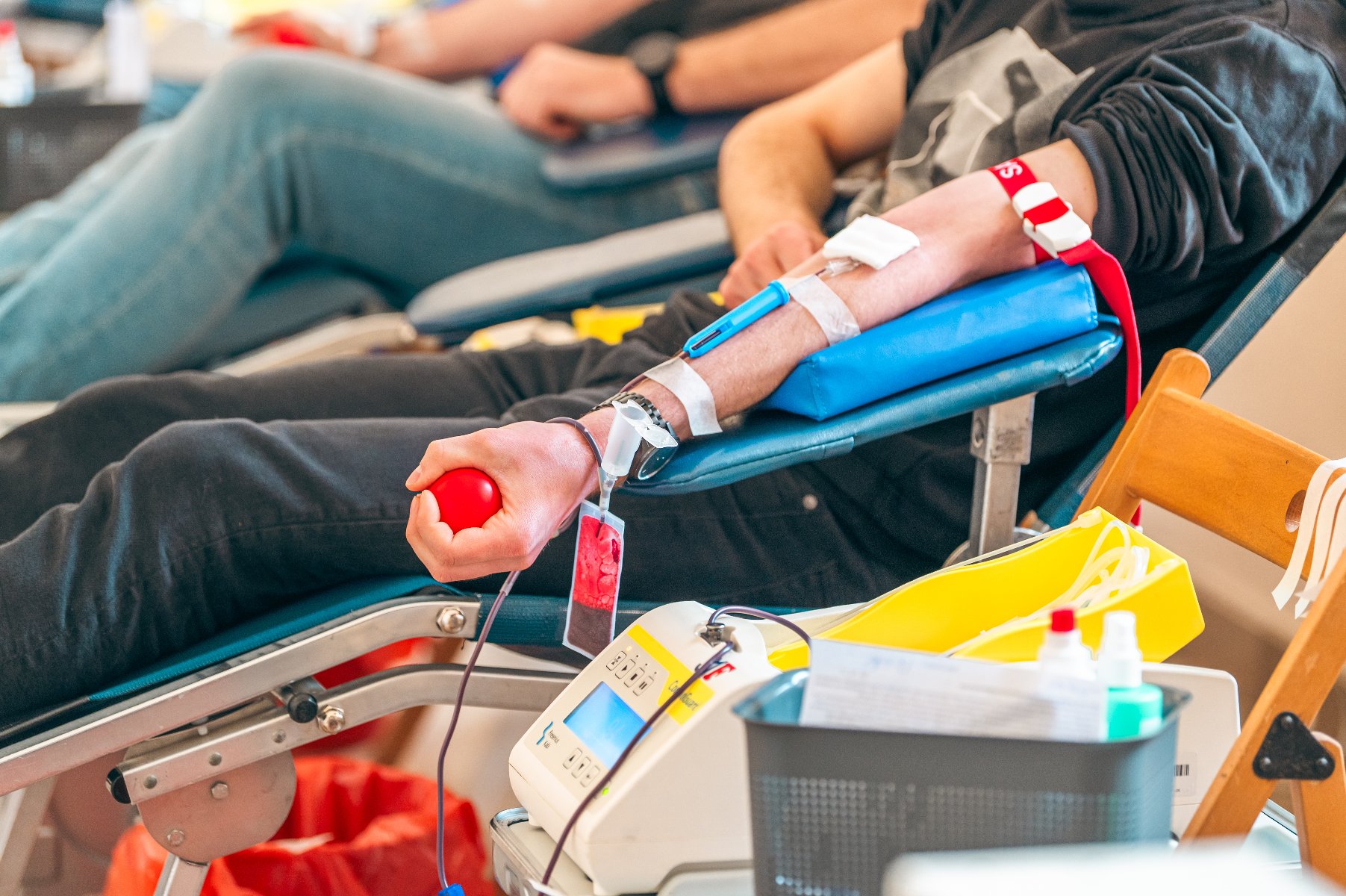 Na zdjęciu osoba oddająca krew, nie widać jej twarzy, w dłoni trzyma czerwoną piłeczkę