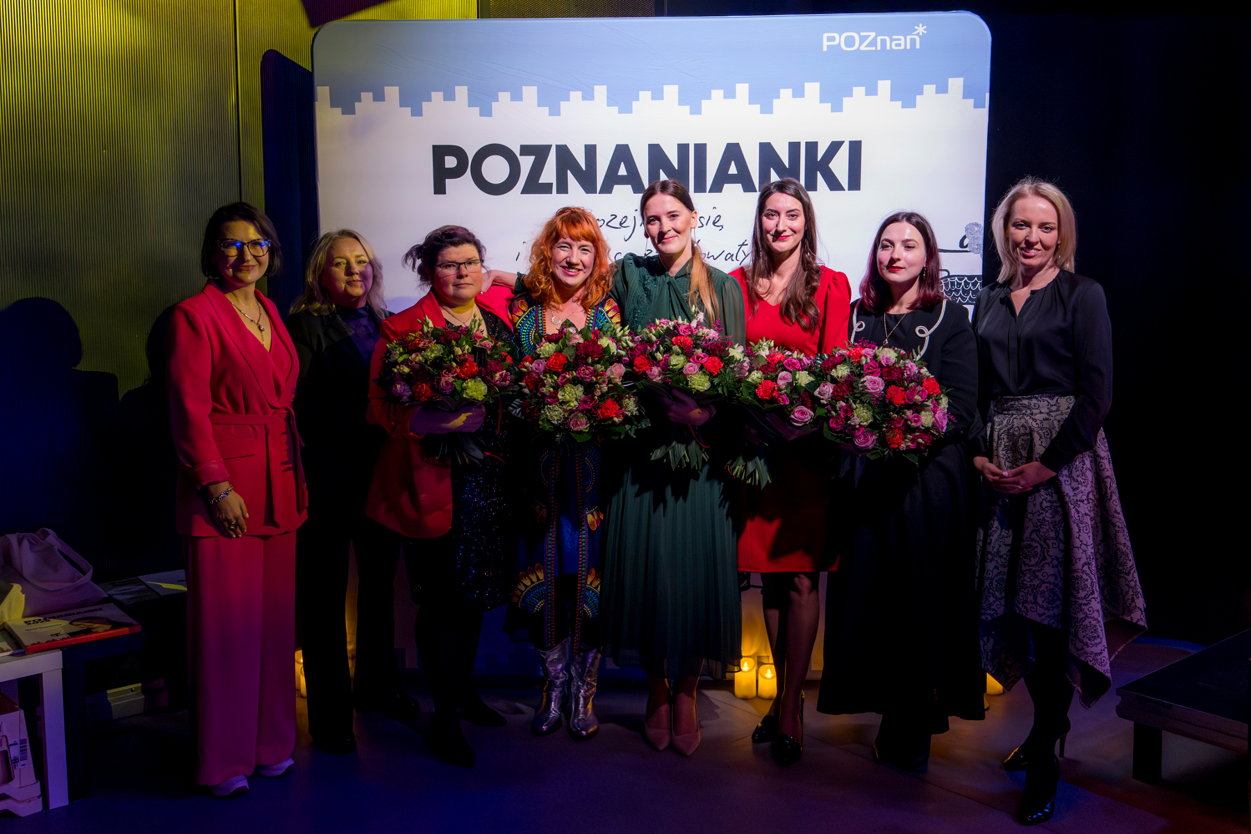 Na zdjęciu pięć uśmiechniętych kobiet, pozujących na ściance