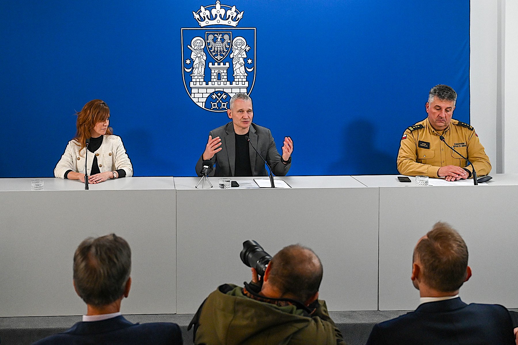 Na zdjęciu trzy osoby za stołem konferencyjnym, w tle ścianka z herbem Miasta