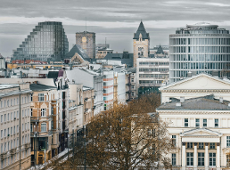 Na zdjęciu widać fragment centrum Poznania. Po prawej stronie widać fasadę Arkadii od strony placu Wolności, a za nią Okrąglak. Po lewej stronie widać ciąg kamienic przy ulicy 27 Grudnia. W tle widać wieże Zamku Cesarskiego oraz biurowiec Bałtyk. Niebo jest szare i zachmurzone. Zdjęcie zostało wykonane z góry.