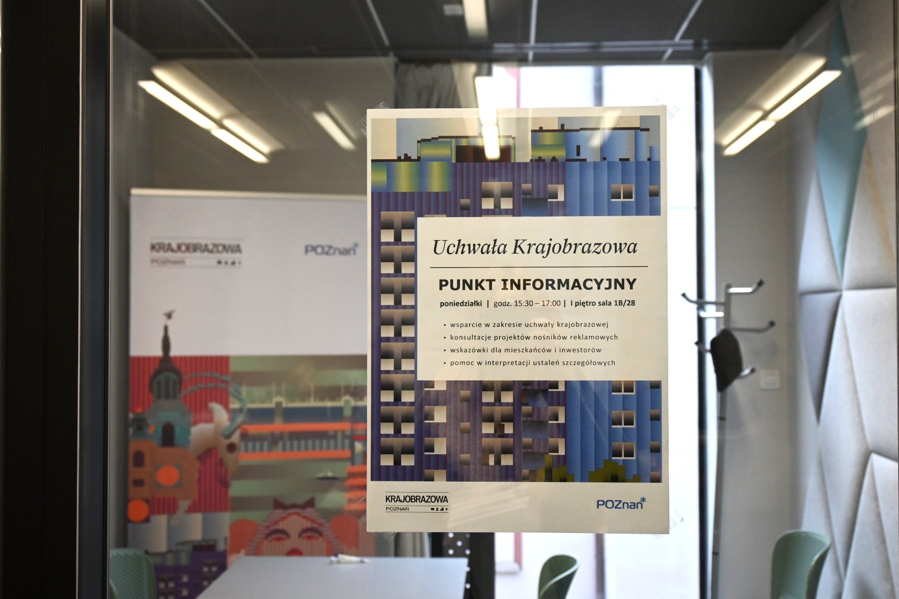 Na zdjęciu widoczny jest plakat informacyjny dotyczący usług punktu informacyjnego. W tle fragment pomieszczenia biurowego, w którym będą odbywać się konsultacje.