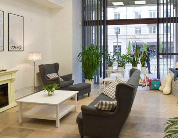 Na zdjeciu wnętrze CIR, widać kanapę, fotel, stolik, obok leżą zabawki, w tle duże okno