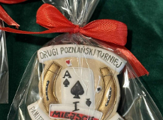 Nagrody w II Turnieju Pamięci Bohaterów Niepodległości 1918, fot. City Park Bridge Club - zdjęcie piernika z motywem podkowy i asa na beżowym tle. Wszystko na tle zielonego materiału