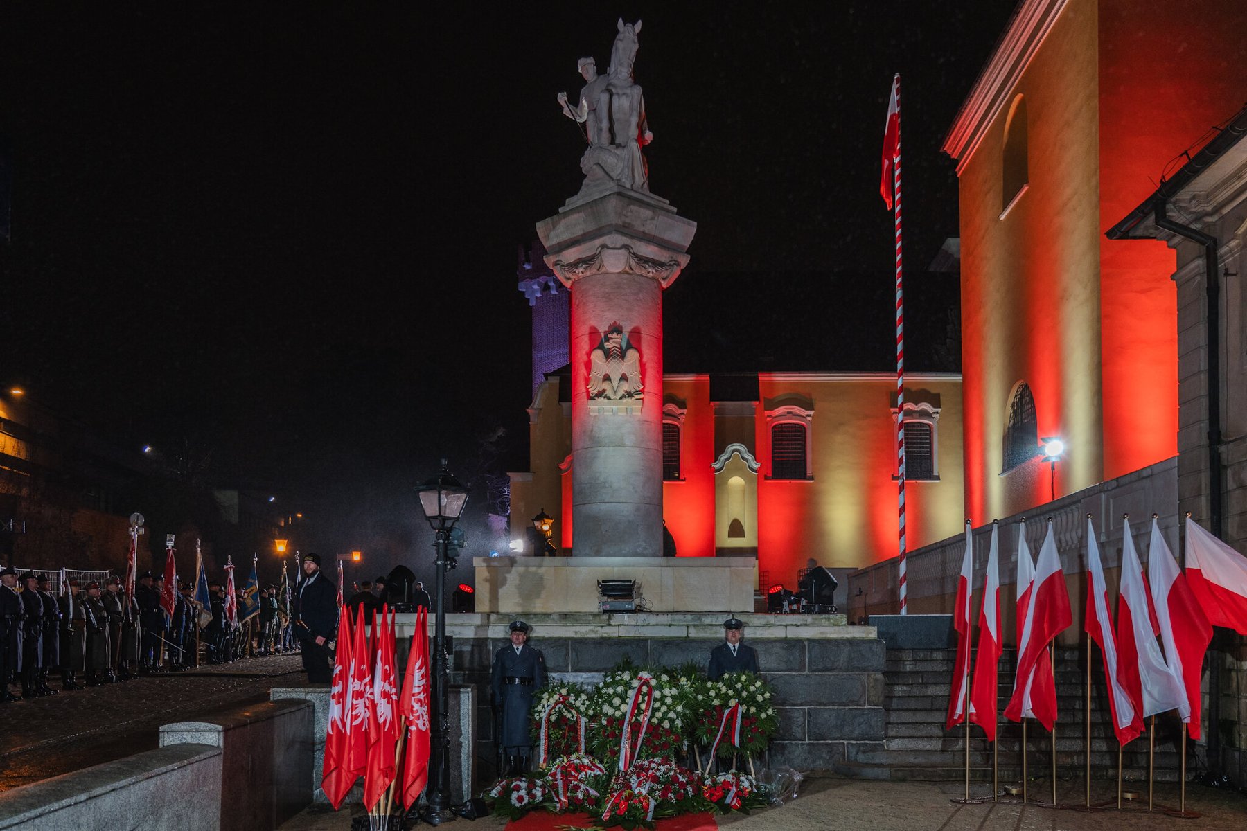 Nocne zdjęcie przedstawiające uroczystość patriotyczną przed Pomnikiem Ułana Poznańskiego w Poznaniu.