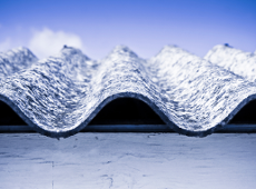 Obraz przedstawia fragment dachu zawierający azbest na tle niebieskiego nieba