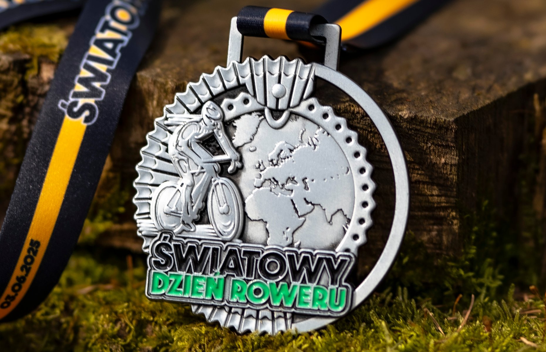 Odlewany medal z napisem Światowy Dzień Roweru. Medal to płaskorzeźba z mapą świata a na niej rowerzysta.