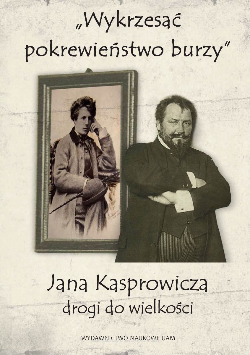 Brodaty mężczyzna z założonymi rękoma stojący przed obrazem wiszącym na ścianie.