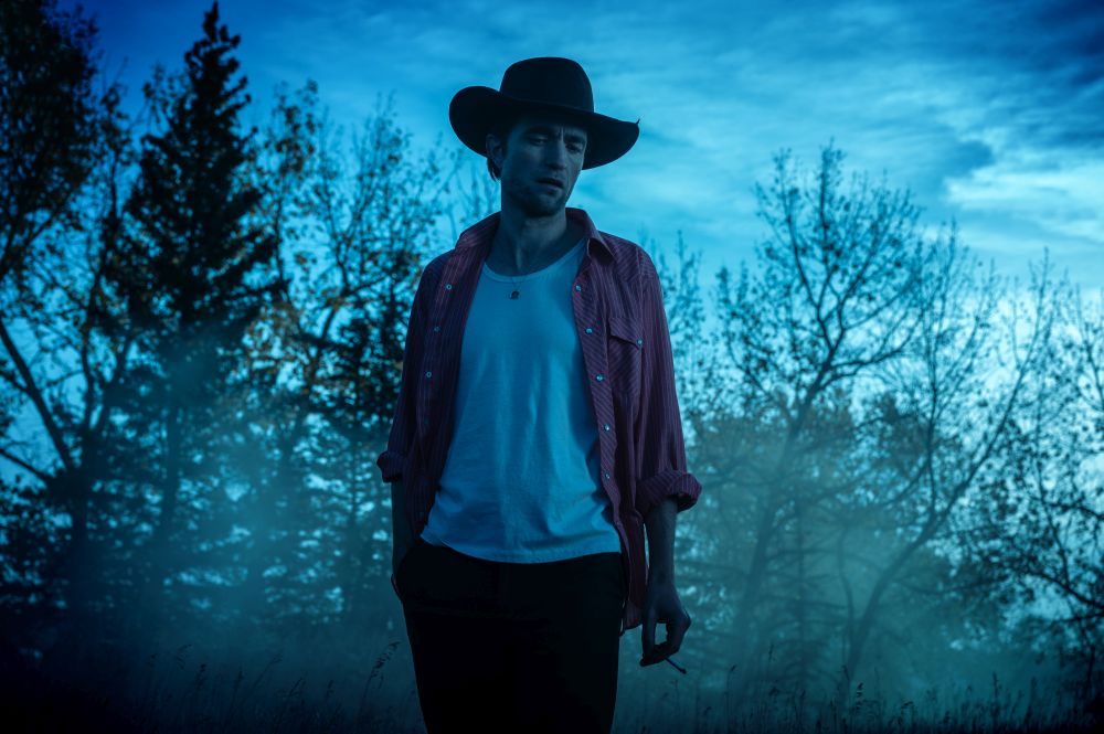 Para w eleganckich ubraniach tańczy wtulona w siebie. Za nimi siedzą i śmieją się inni goście przyjęcia.