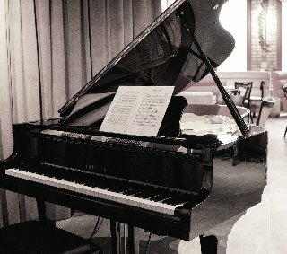 Czarno-białe zdjęcie fortepianu, na którym rozłożono nuty.