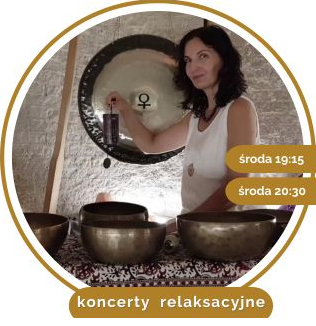 Kobieta w białej bluzce siedzi na dywanie. Przed nią stoją misy i gongi do grania.