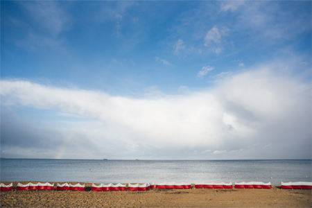 Plaża - obraz niebo, morze i piaszczysta plaża.Na plaży biało-czerwone parawany.