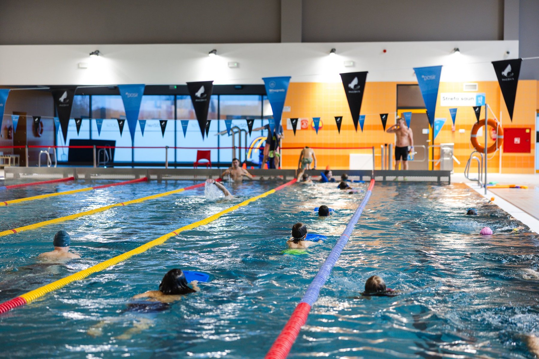Pływalnia Winogrady, fot. Andrzej Olszanowski - ludzie pływają w basenie, w tle ratownicy pilnujący pływaków