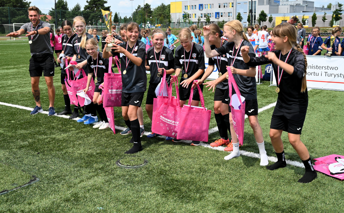 Poznańska Liga Orliczek, fot. RaJu Photography - młode zawodniczki cieszą się, jedna trzyma puchar, a wszystkie mają medale na szyi i różowe siatki