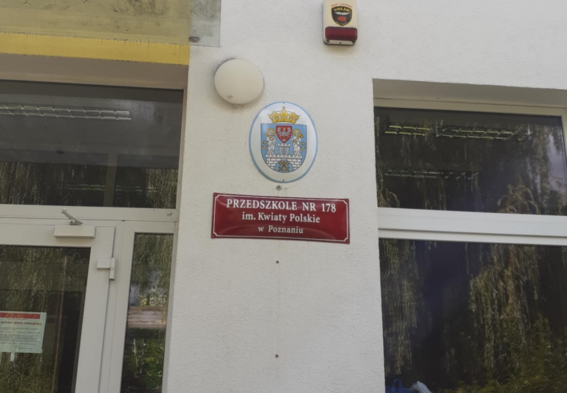 przed wejściem do przedszkola na ścianie herb Poznania i tablica z nazwą przedszkola