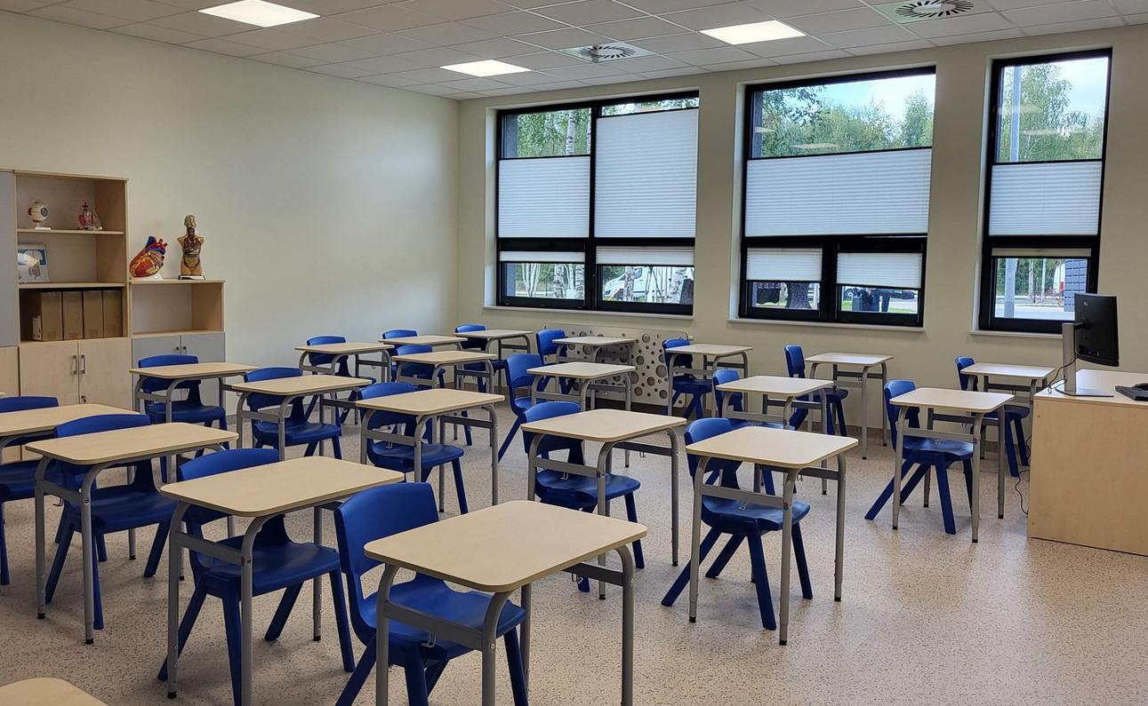 Pusta sala lekcyjna w szkole, ławki i krzesła, pod ścianą szafki i pomoce naukowe