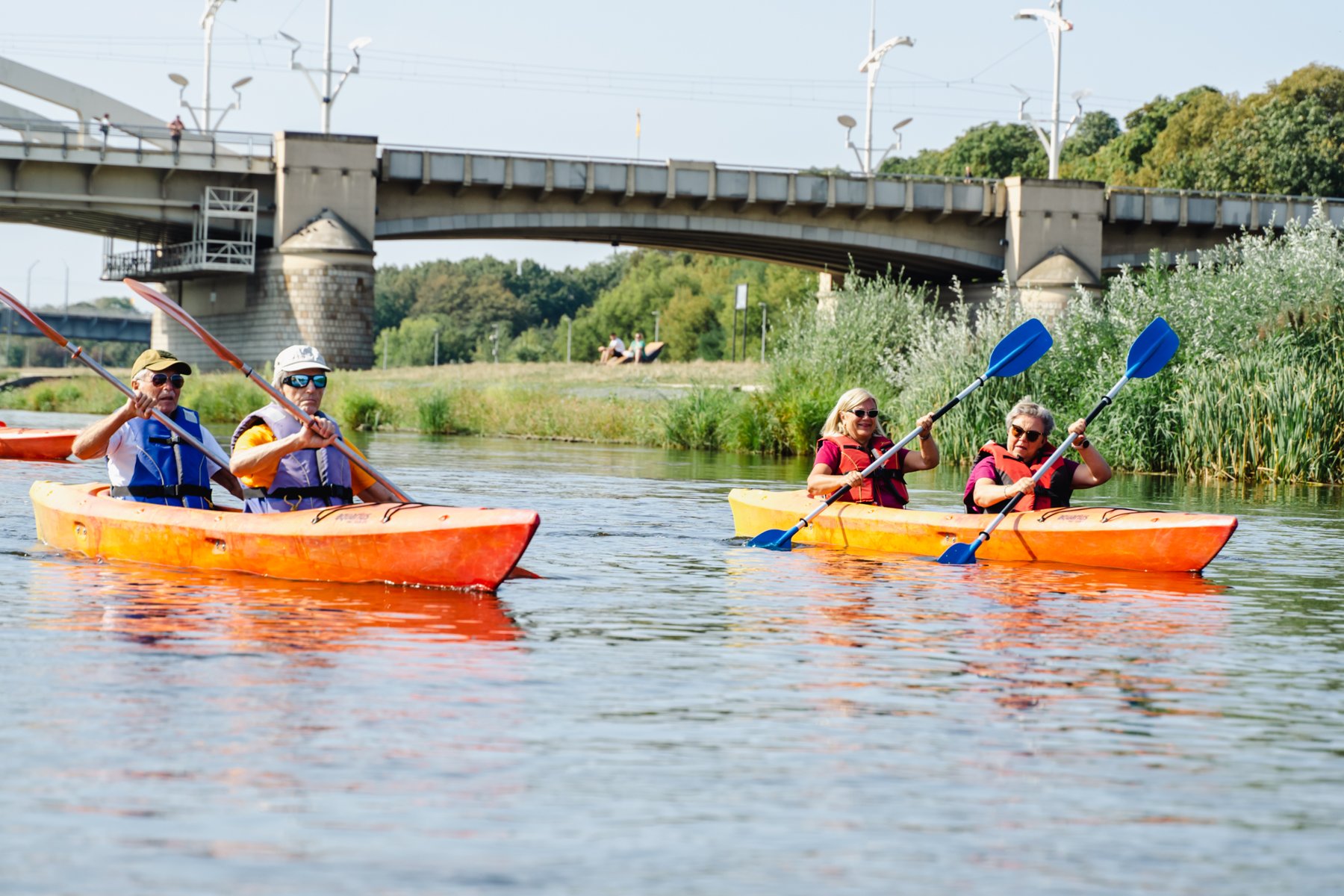 Seniorzy na kajakach pływają po Warcie