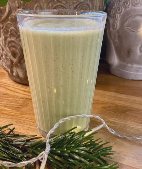 Szklanka z zielonym smoothie, przed którą leży świerkowa gałązka