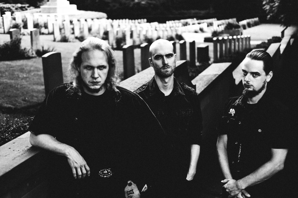 Trzech mężczyzn stoi na cmentarzu.